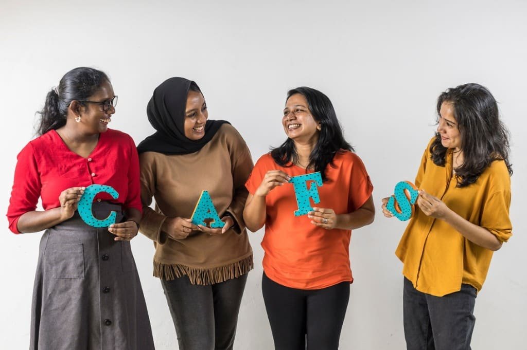 Four smiling team members holding letters that spell CAFS